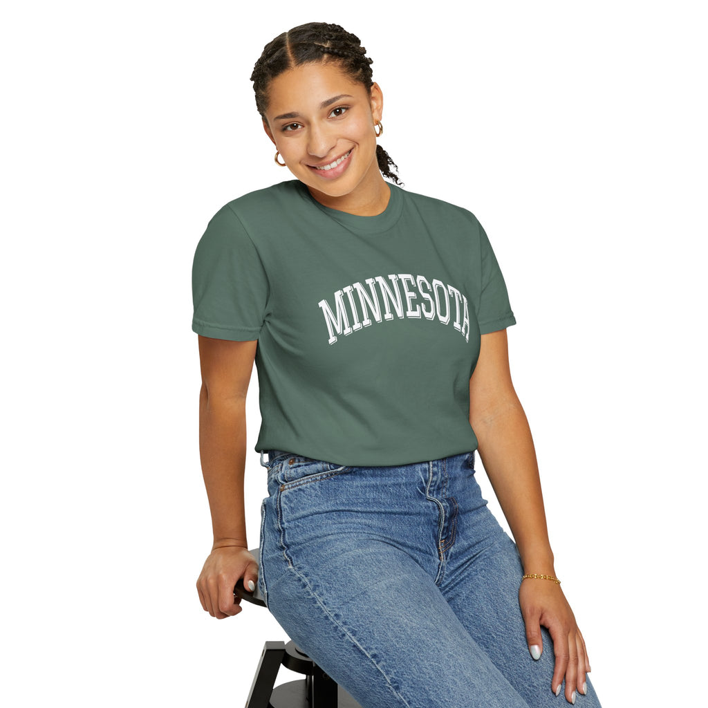 Person wearing a green 'MINNESOTA' t-shirt and blue jeans on a white background