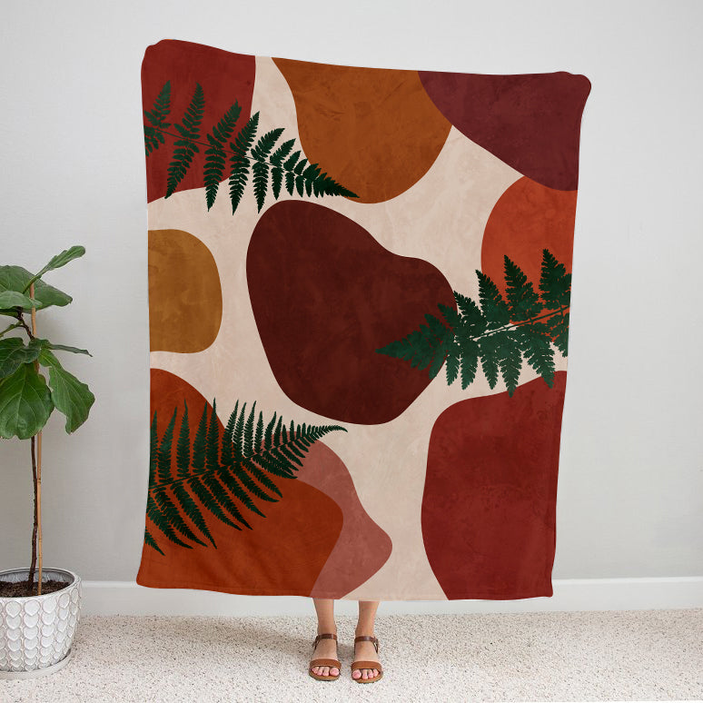 Decorative blanket with abstract patterns and green leaves on a neutral background