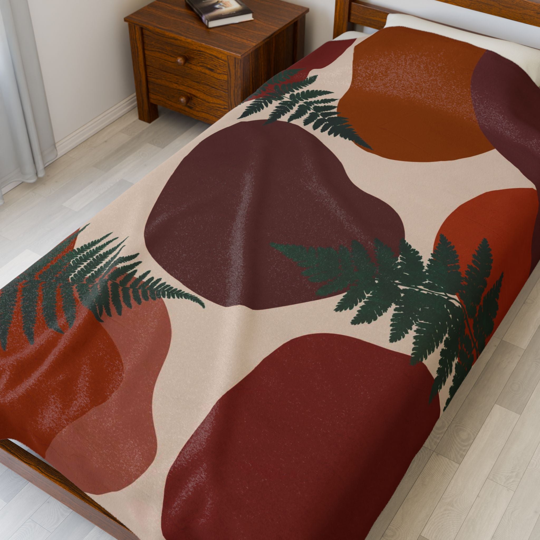 Throw blanket with abstract leaf design and geometric pattern on a bed in a bedroom setting