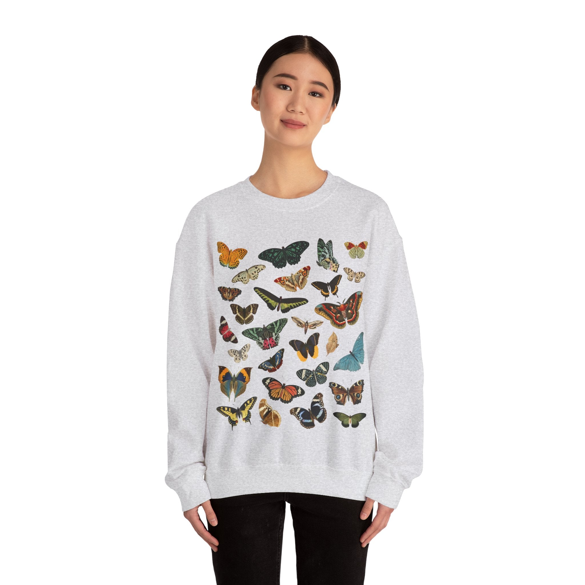 Person wearing a light ash gray sweatshirt with colorful butterfly patterns on a white background