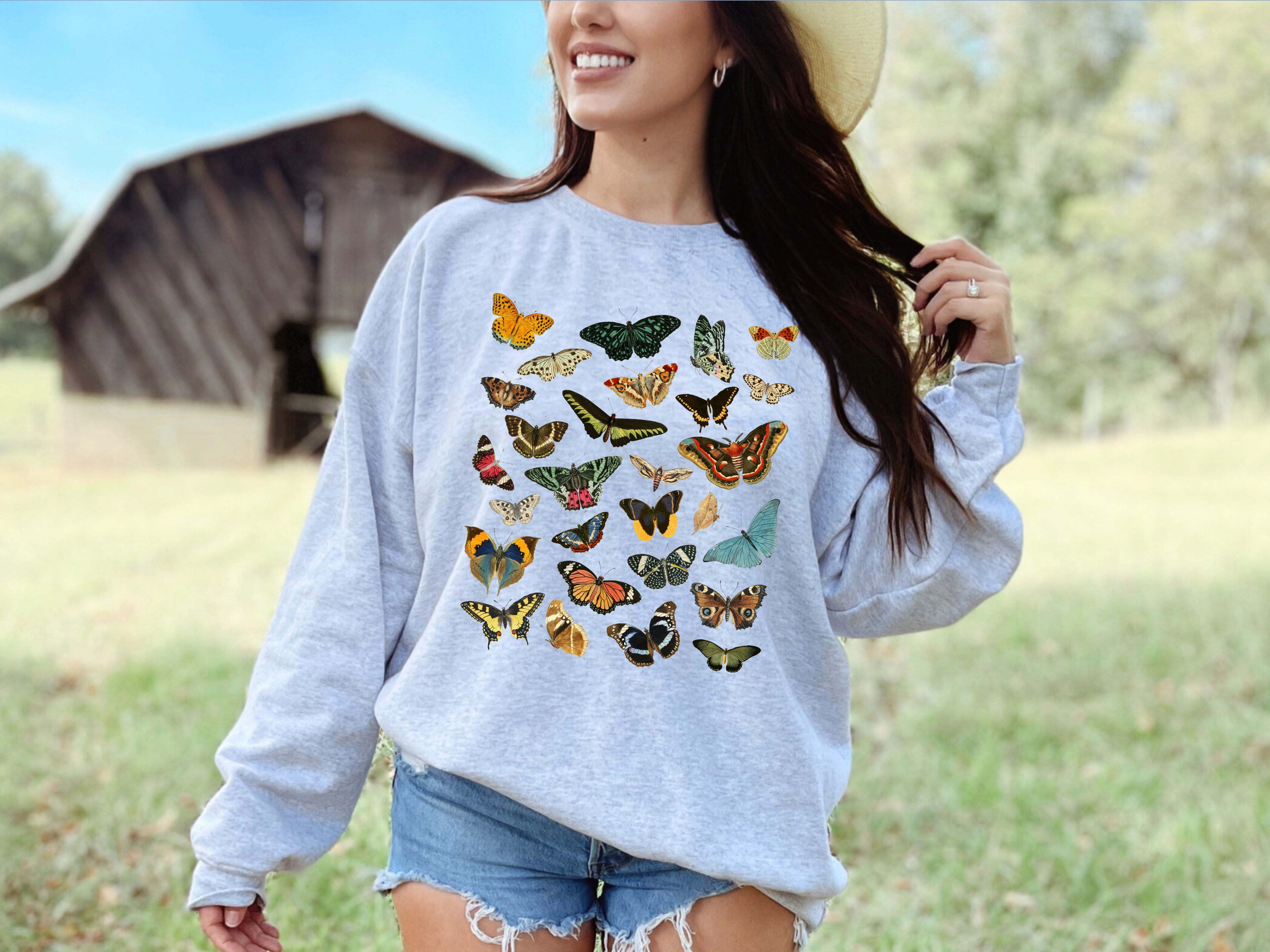 Woman wearing a ash gray sweatshirt with butterfly designs outdoors.