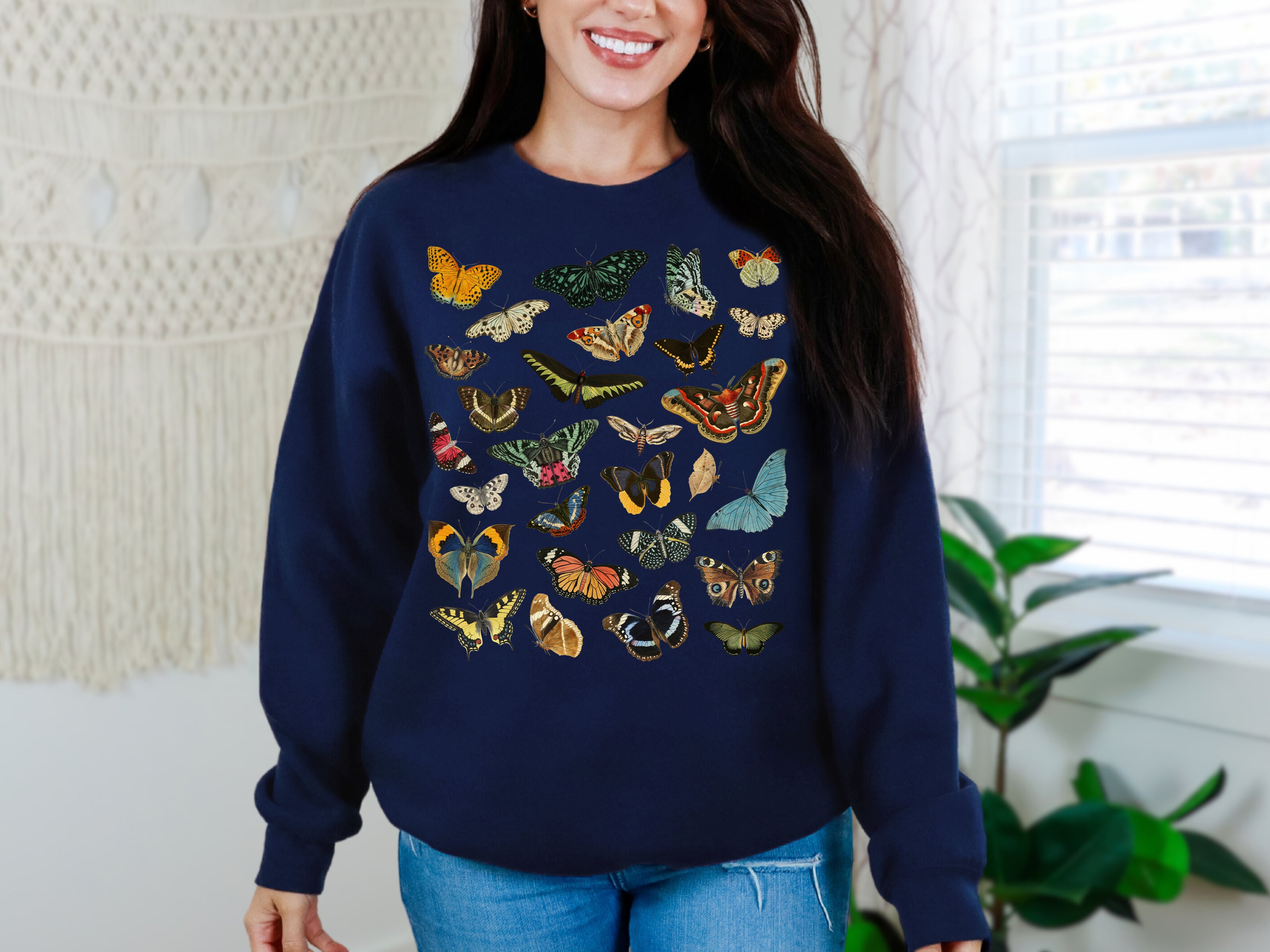 Woman wearing a navy blue sweater with colorful butterfly patterns in a home setting.