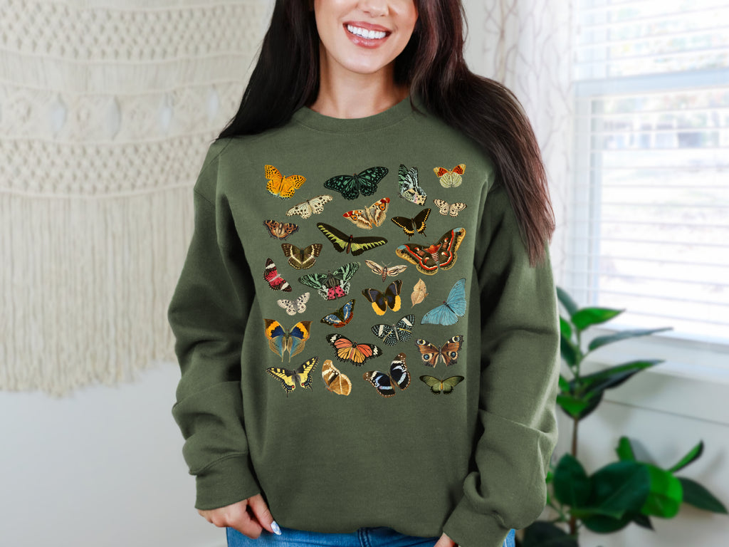 Woman wearing a Gildan Military green sweatshirt with butterfly designs in a home setting