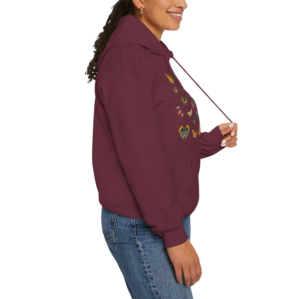 Person wearing a maroon hoodie with floral embroidery on a white background