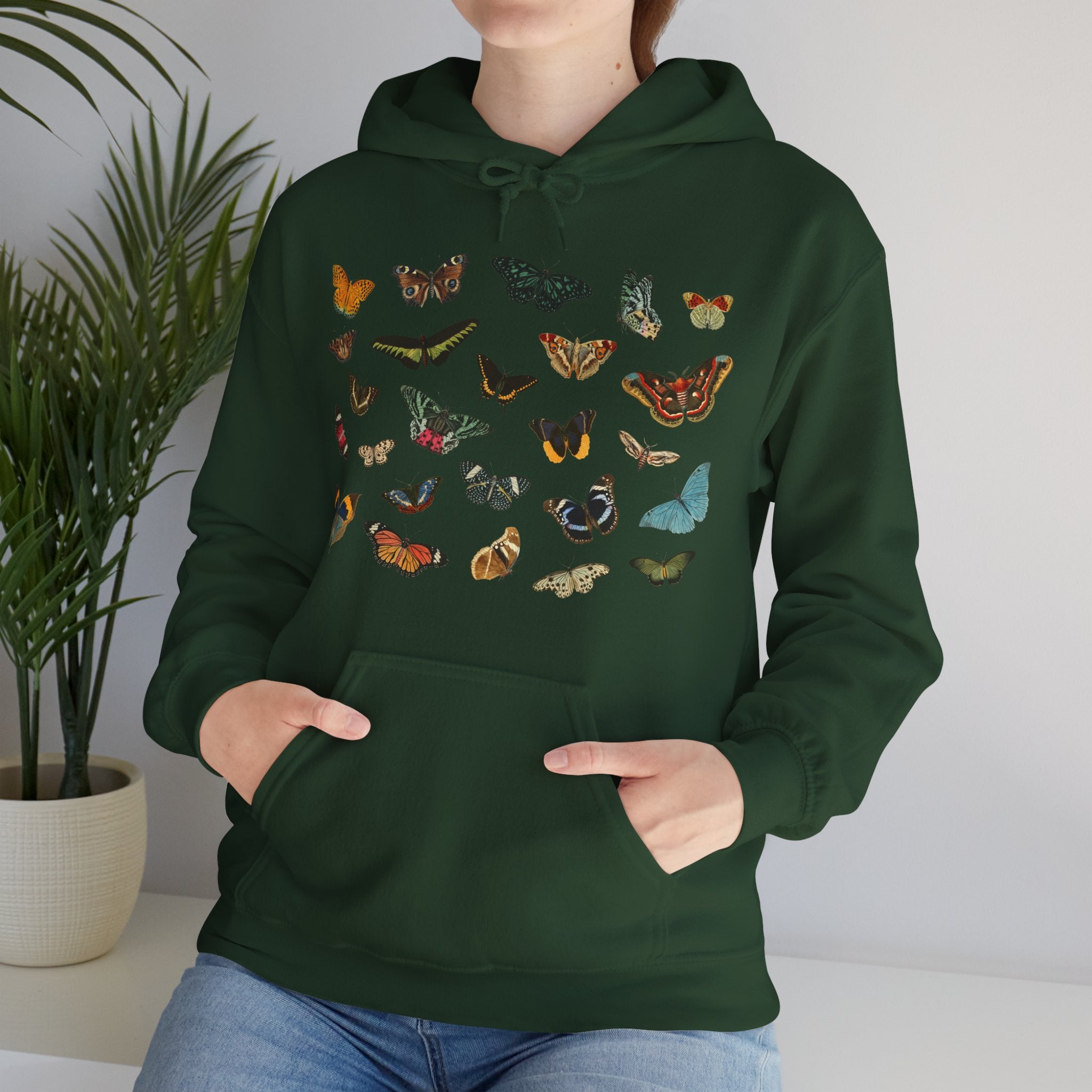 Person wearing a forest green hoodie with butterfly & moth designs against a neutral background, Gildan Forest green sweatshirt