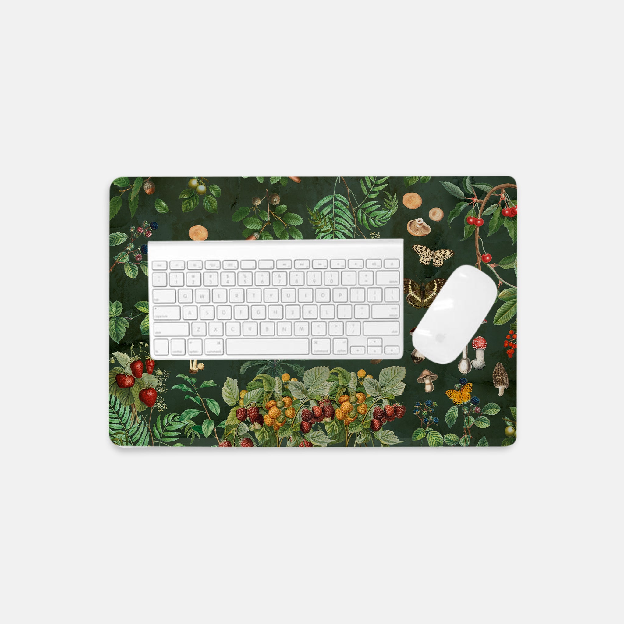 Rectangular Desk mat with nature-themed design featuring plants, mushrooms, and fruits on a dark green background. Keyboard and mouse on top to show sizing.