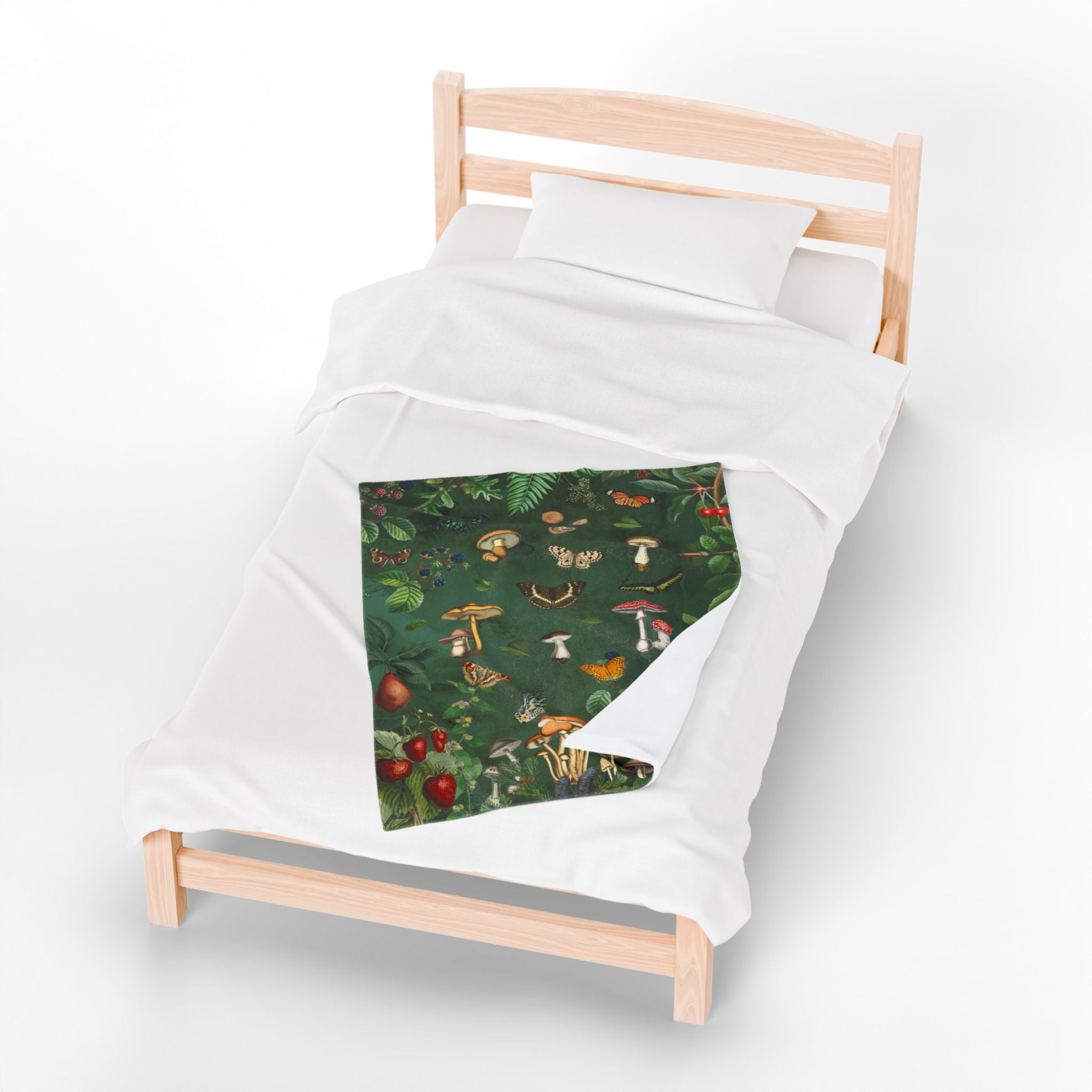 Small bed with a green mushroom-patterned blanket on a white background.