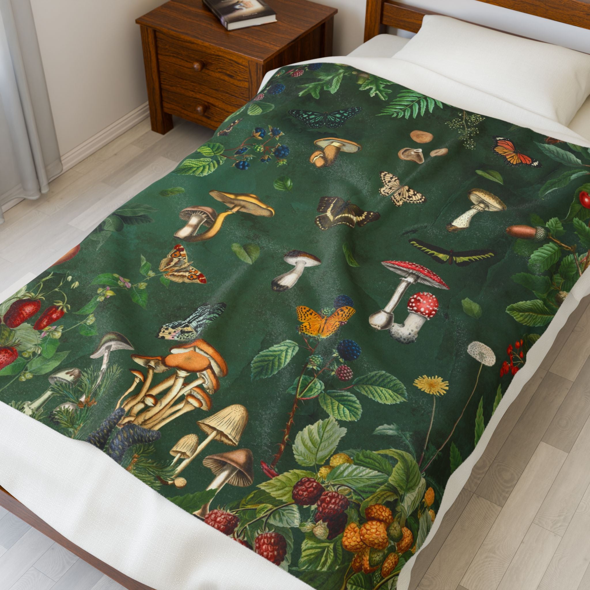 Bed with a throw blanket featuring a nature-themed design featuring mushrooms, butterflies, and plants on a green background.