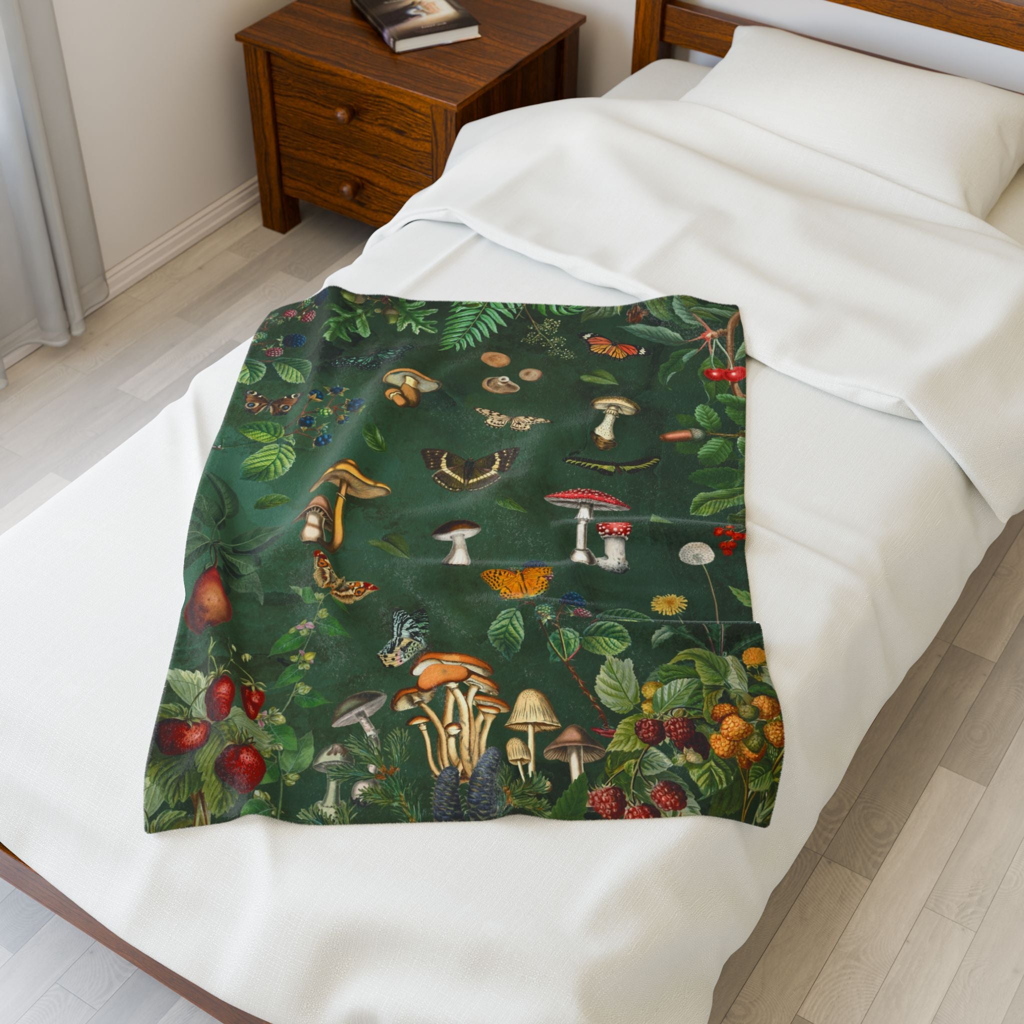Bed with 30x40 inch Cottagecore mushroom velveteen plush blanket with vintage forest illustrations, butterflies, berries, and greenery on a deep green background