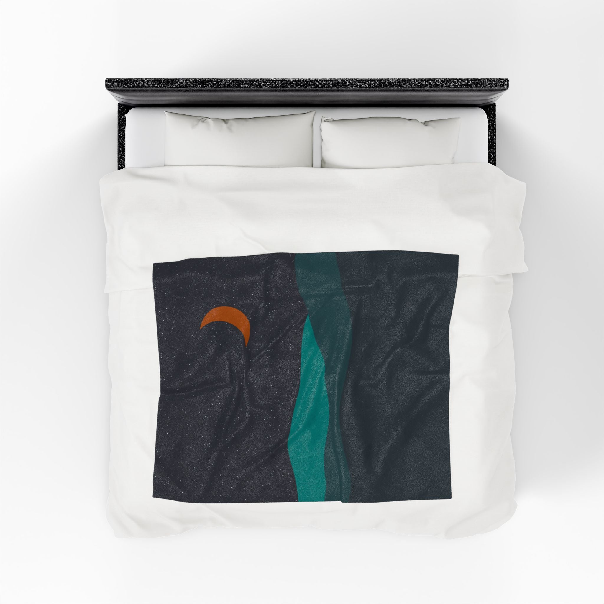 Bed with white bedding and throw blanket featuring abstract desert design with a crescent moon. Shades of teal and deep navy. 