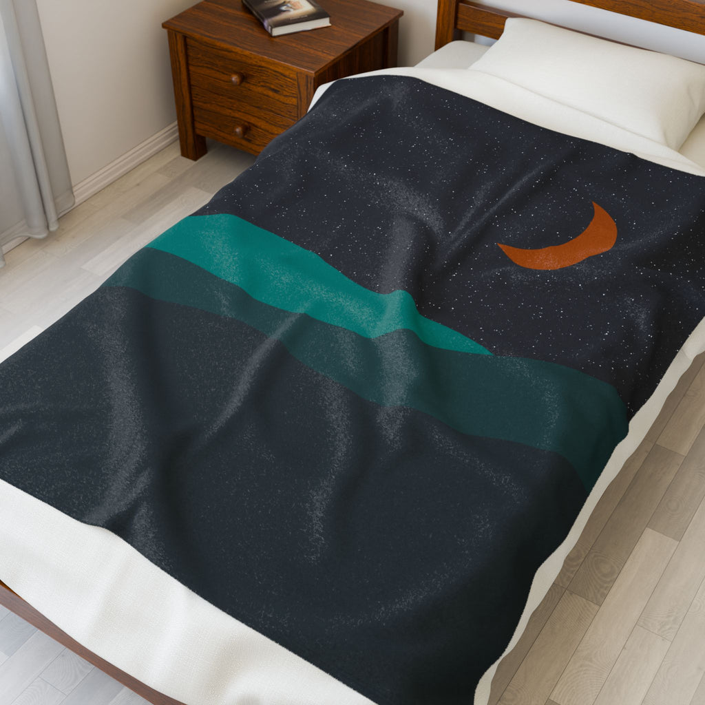 Black blanket with a crescent moon design draped over a bed in a bedroom.