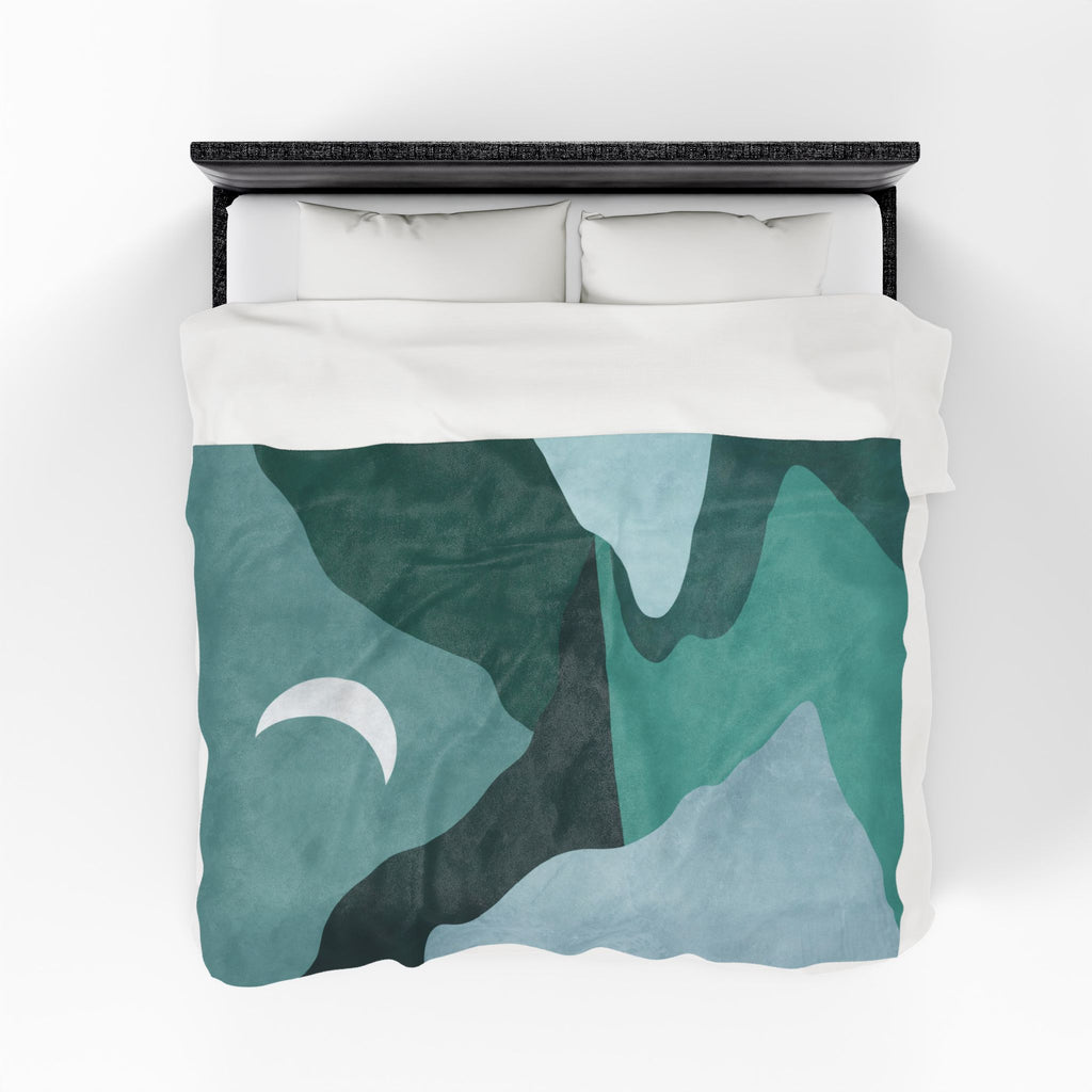 Bed with green and blue abstract patterned throw blanket on a white background