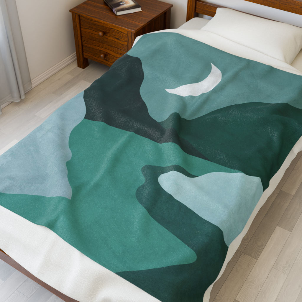 Green and white abstract mountain patterned blanket on a bed in a bedroom. 50x60 inch blanket on a twin bed.