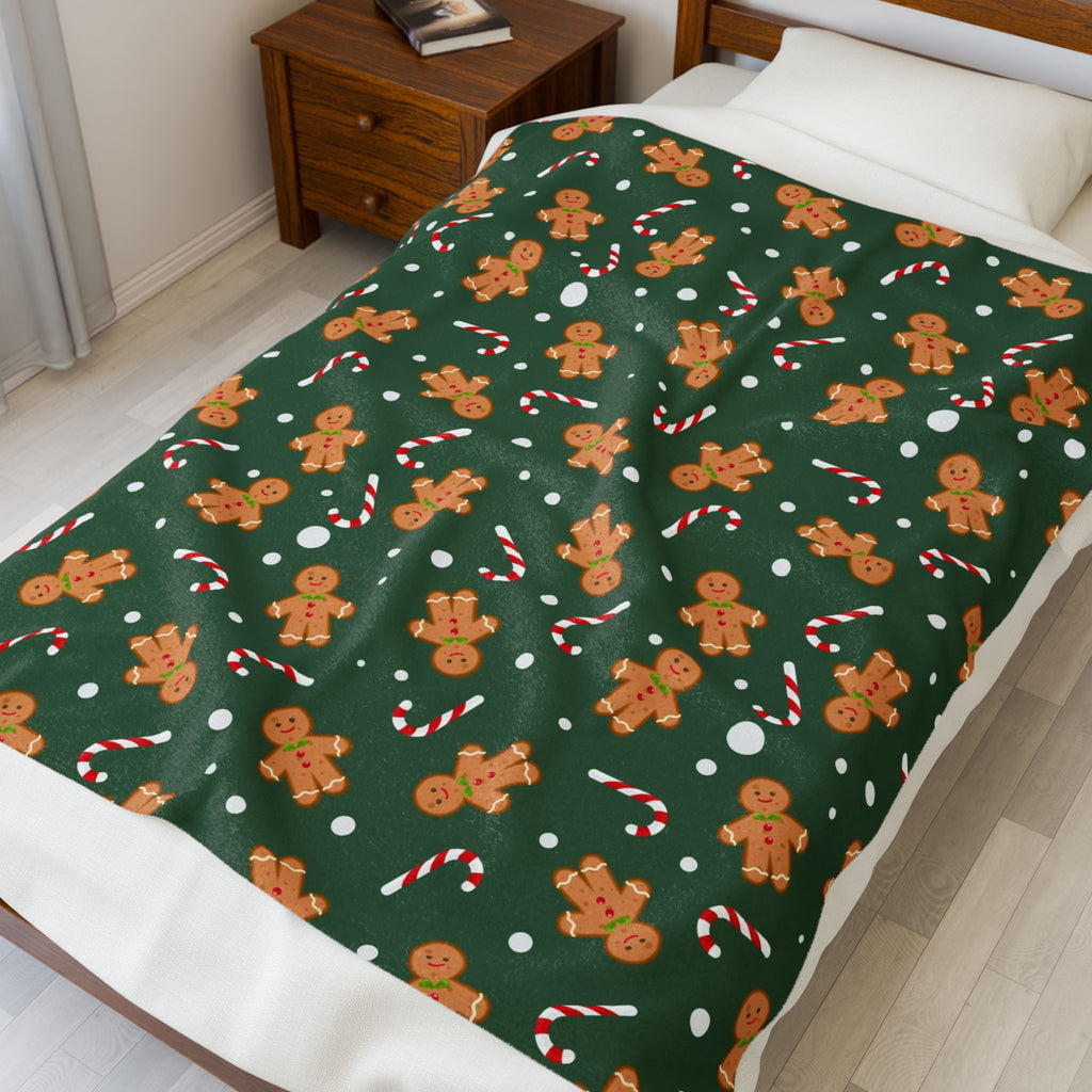 Green blanket with gingerbread man and candy cane pattern on a bed.