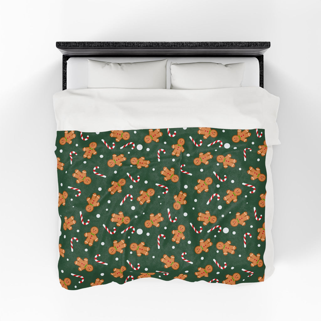 Bed with gingerbread man and candy cane patterned throw blanket on a white background