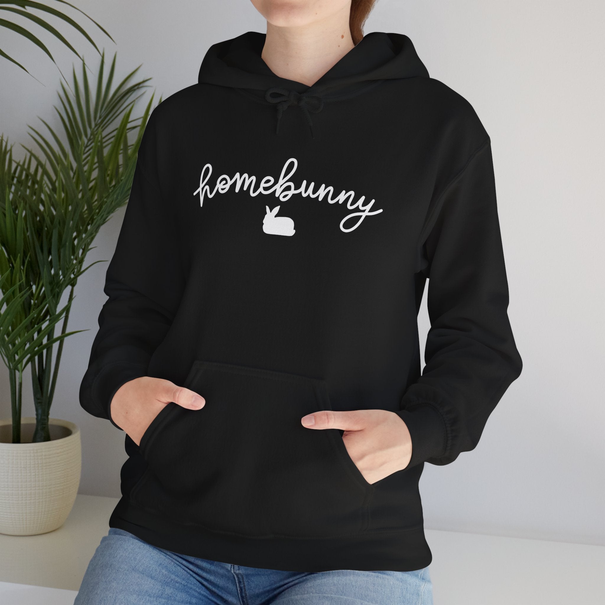 Person wearing a black hoodie with 'homebunny' text and a carrot graphic, standing indoors.