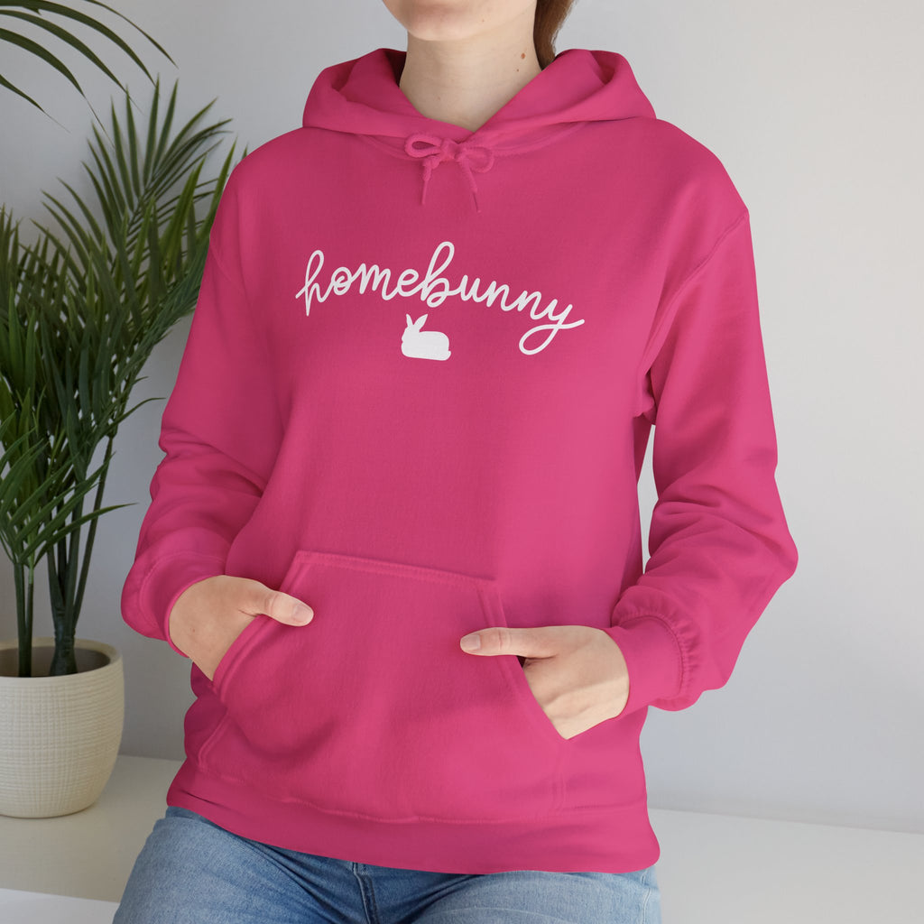 Person wearing a heliconia pink hoodie with 'homebunny' text and logo indoors.