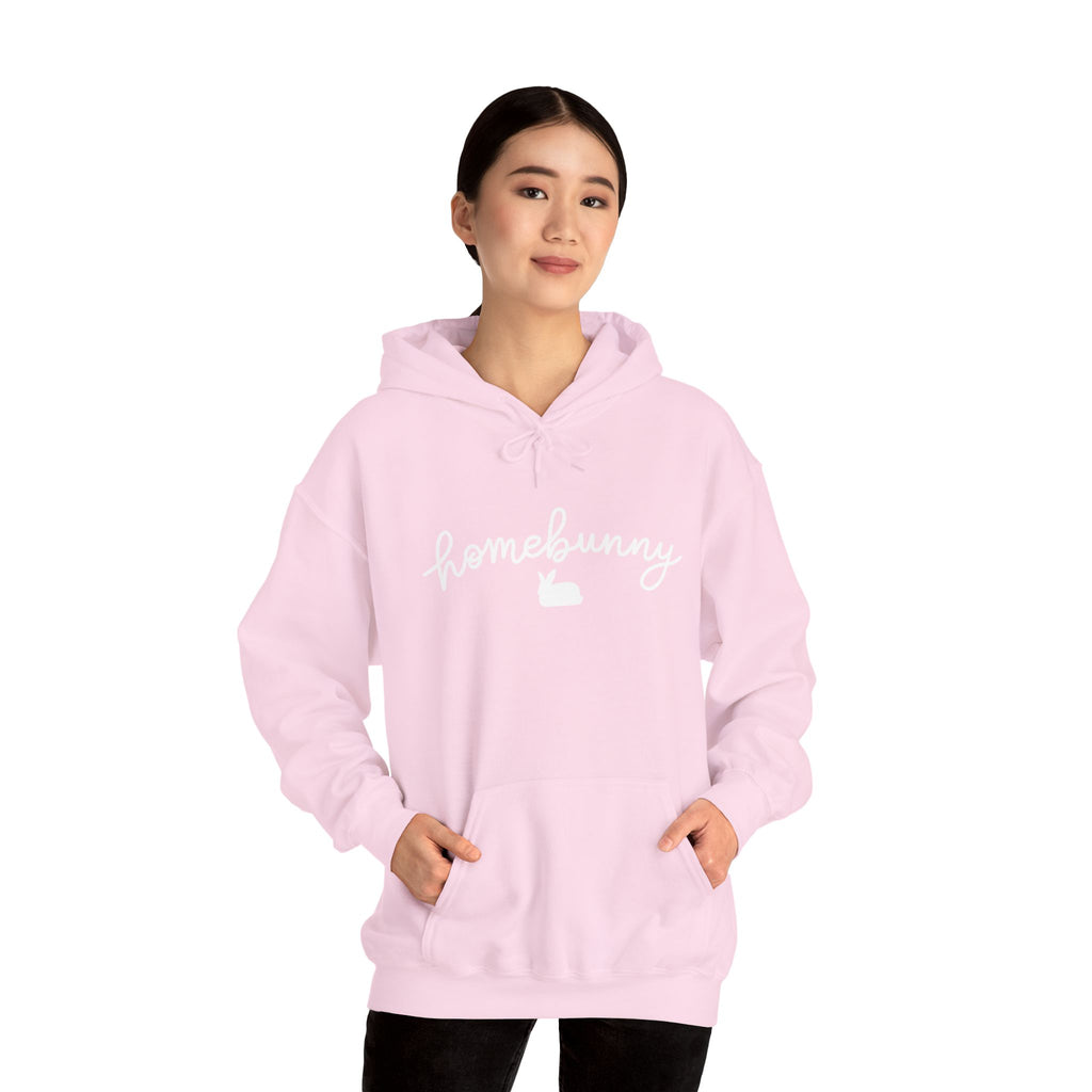 Person wearing a light pink hoodie with 'homebody' text on a white background