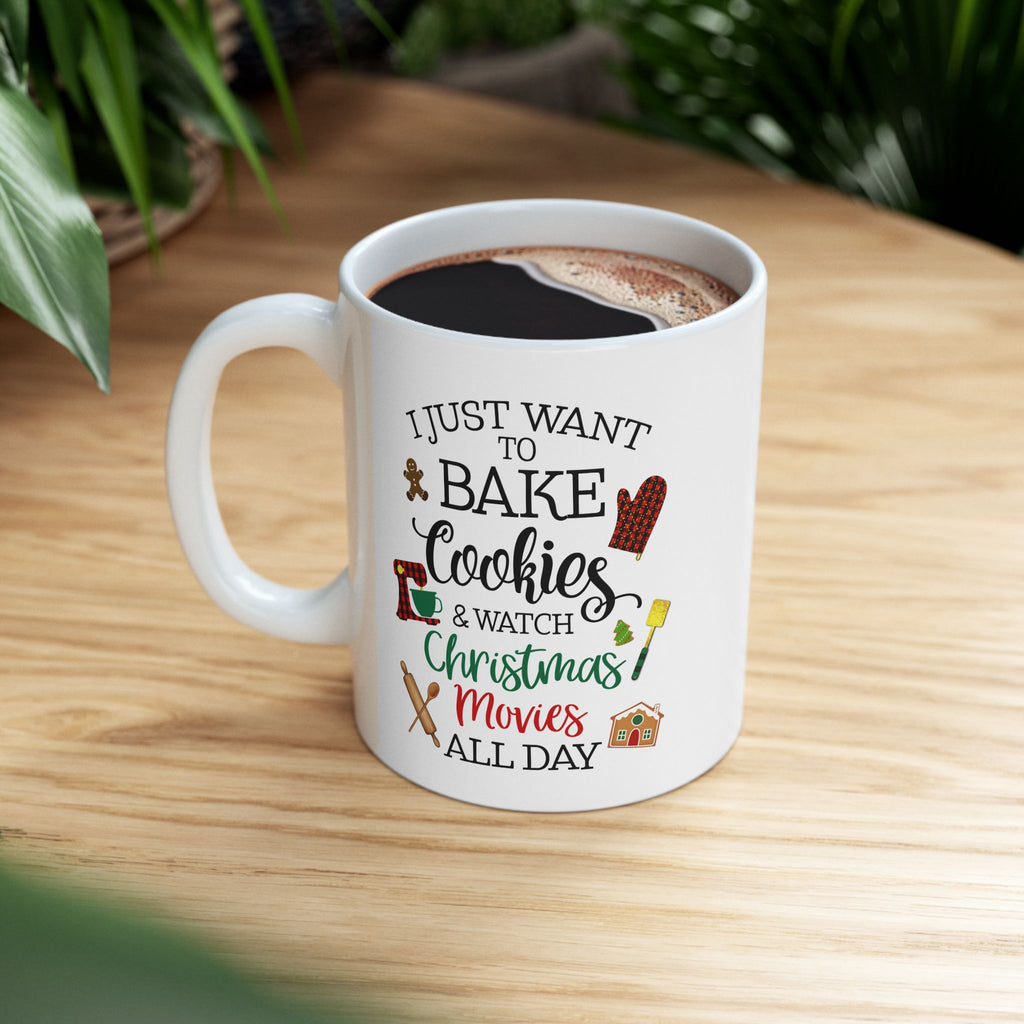 White mug with text 'I just want to bake cookies & watch Christmas movies all day' on a wooden table.