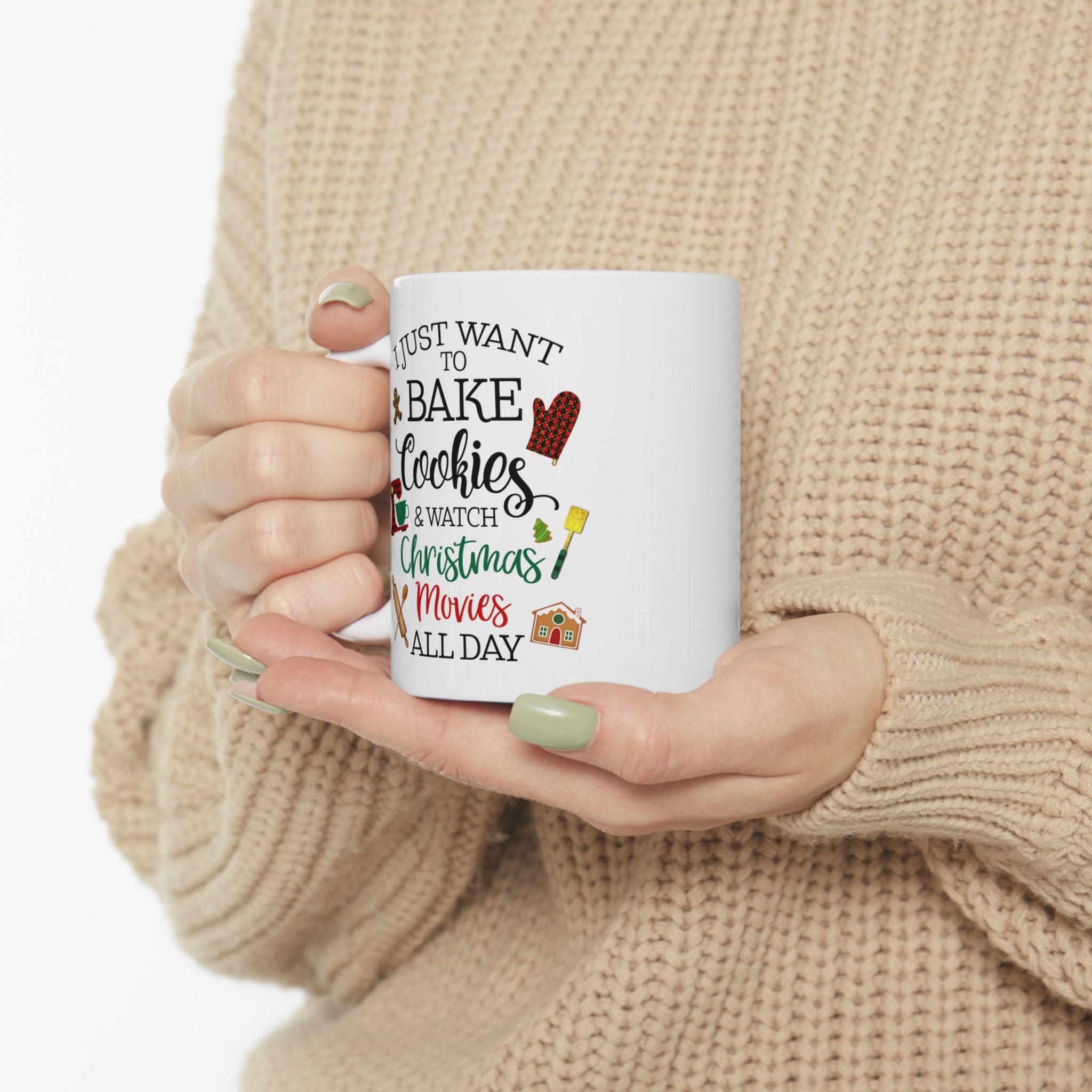 Person holding a Christmas mug with text and graphics, wearing a beige sweater.