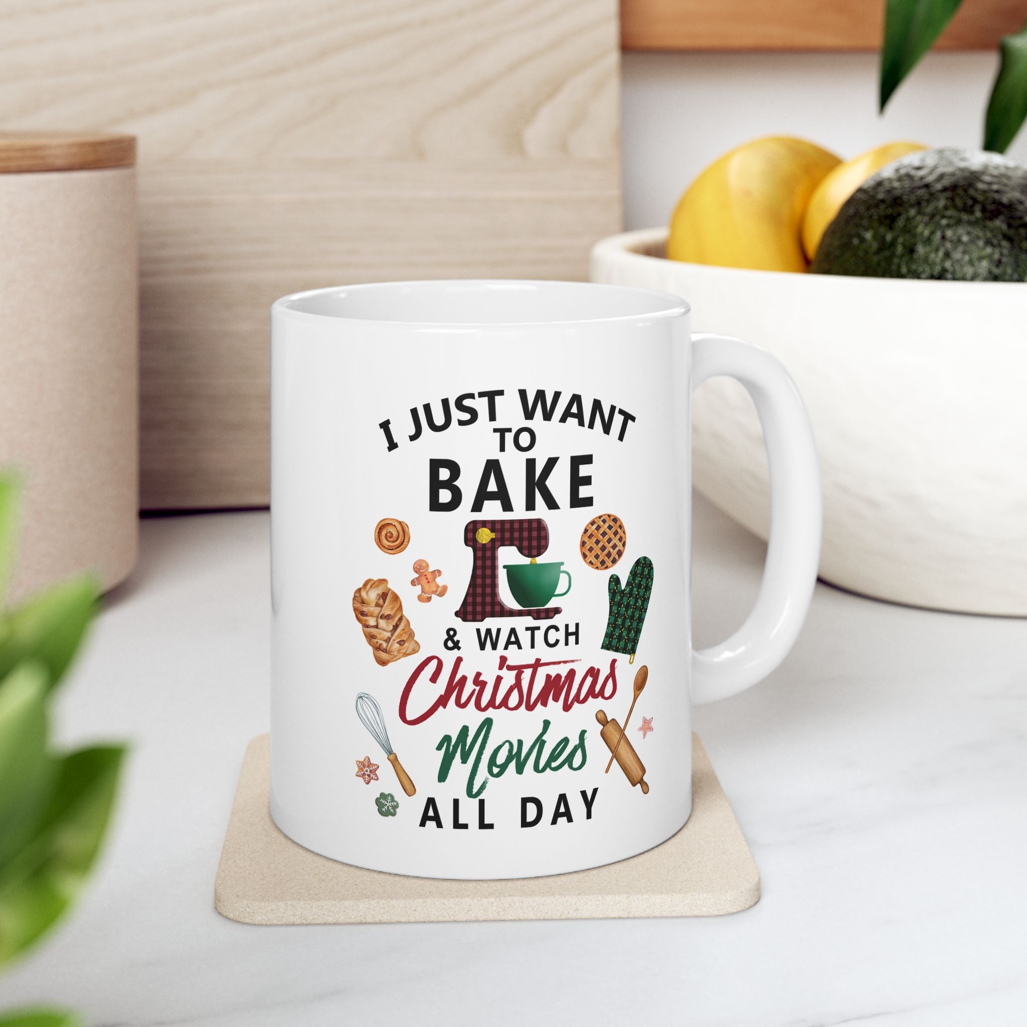White mug with text and Christmas graphics on a coaster, surrounded by kitchen items. Christmas movie mug