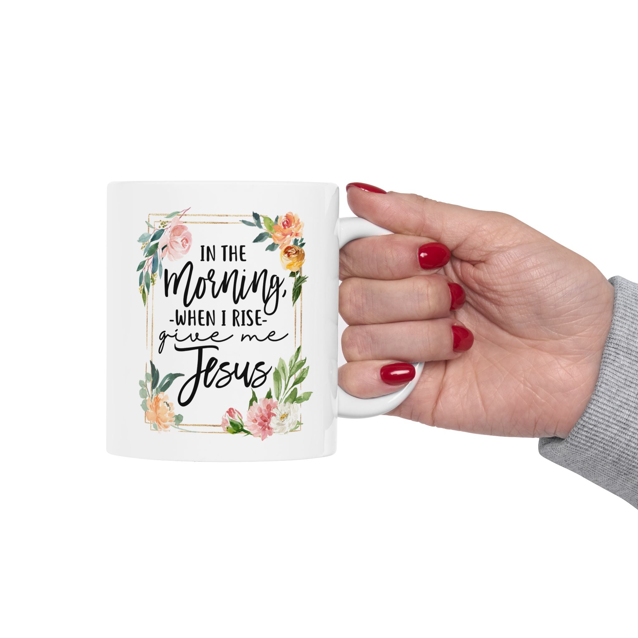 Mug with floral design and text held by a hand on a white background