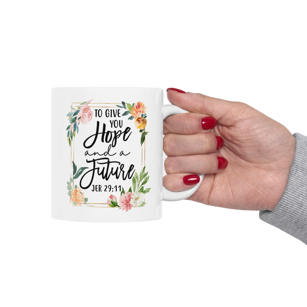 Mug with floral design and text held by a hand on a white background