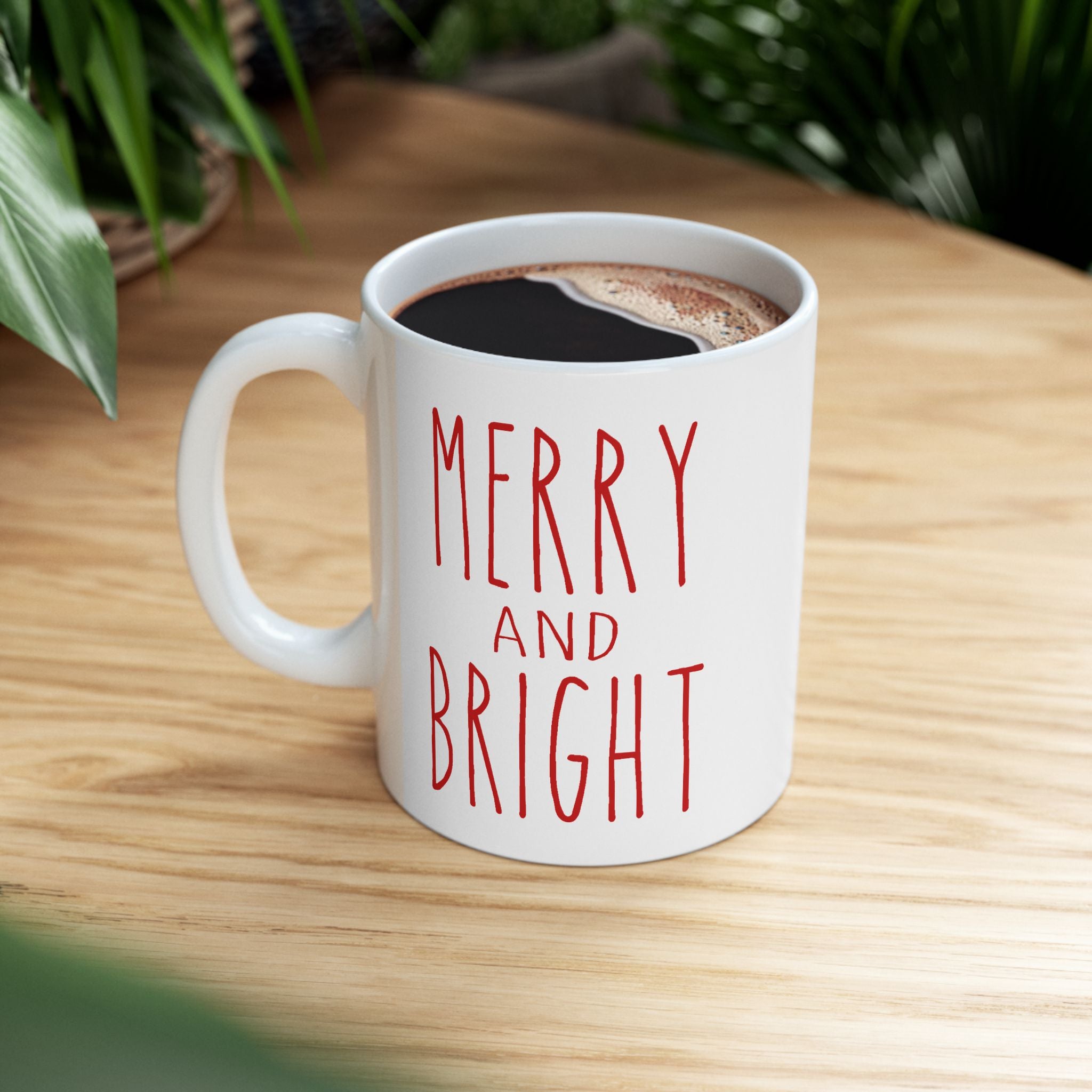 White mug with 'Merry and Bright' text on a wooden table