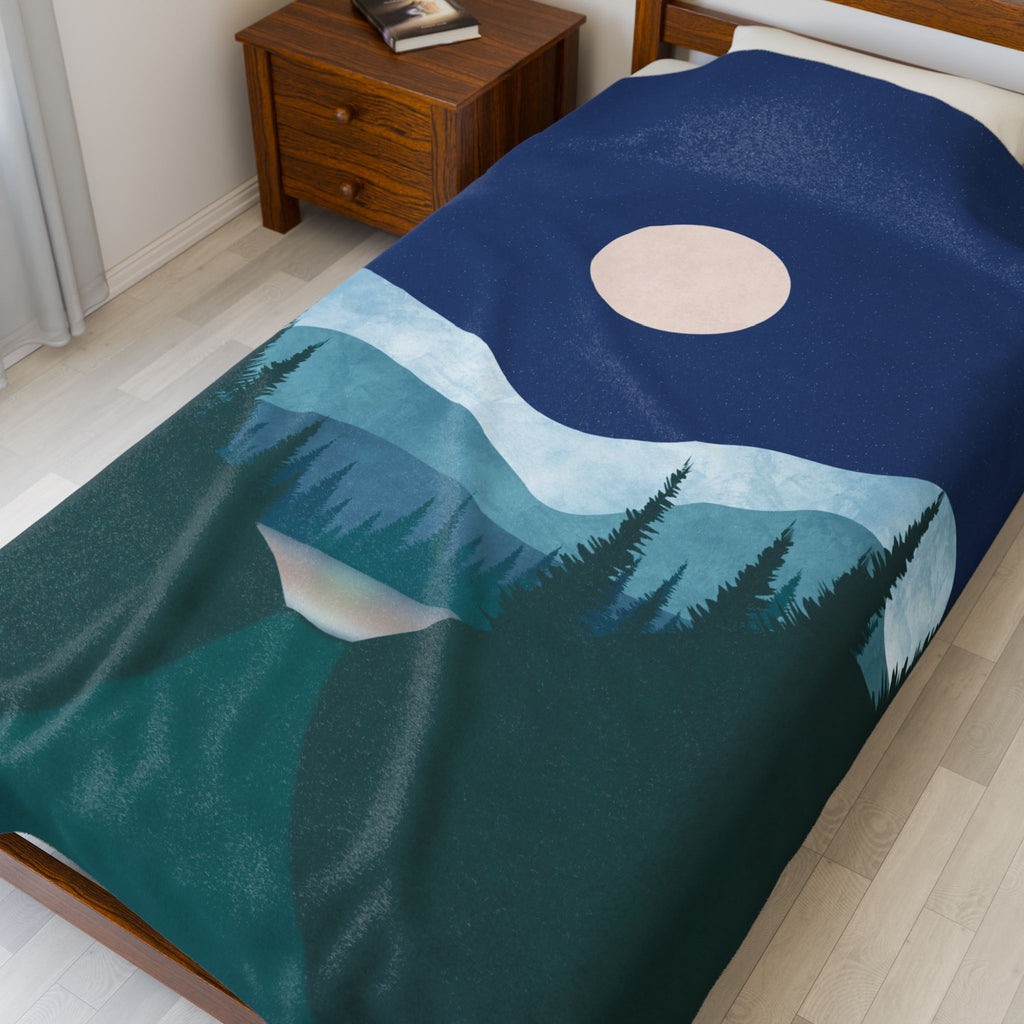 Blanket with mountain and moon design draped over a bed in a bedroom.
