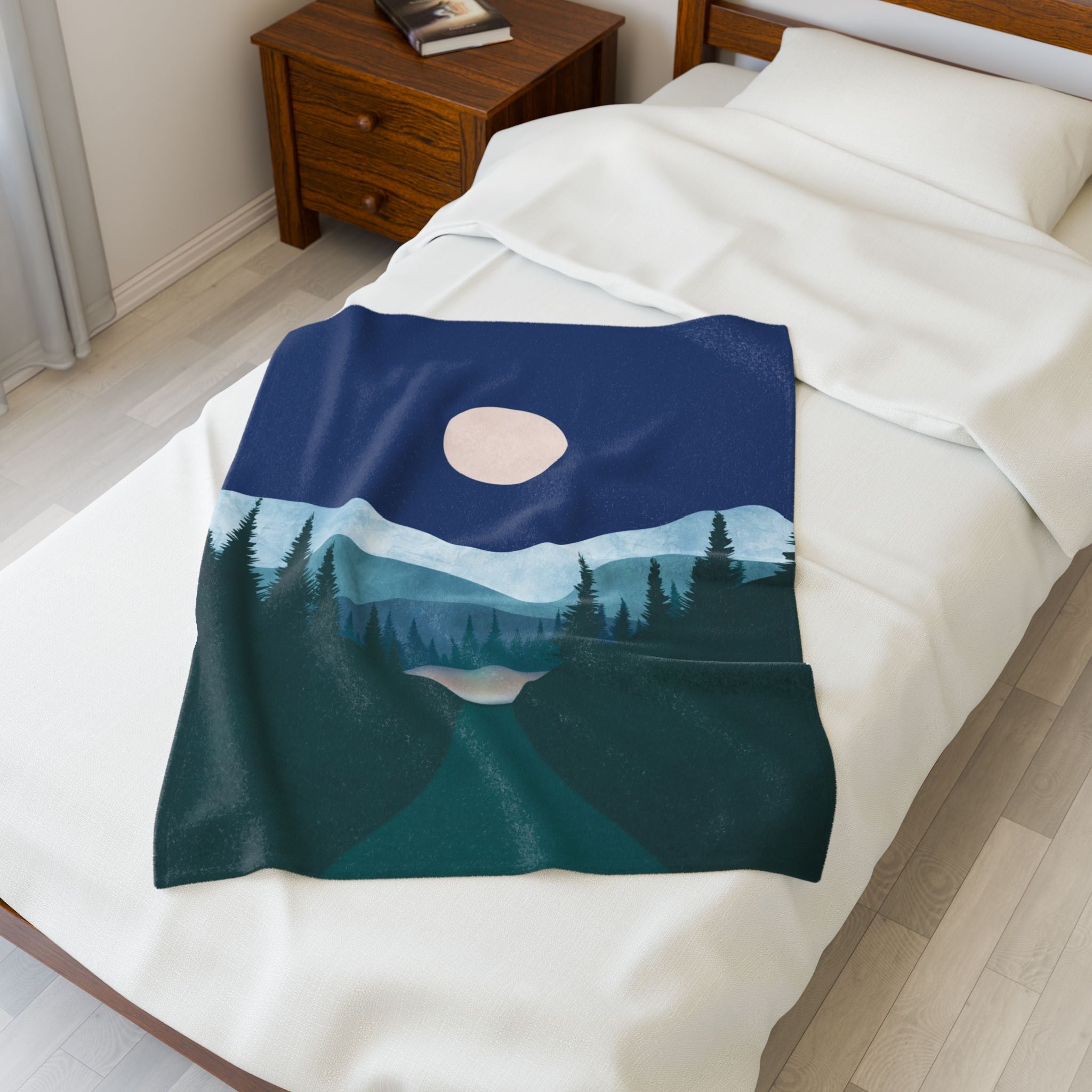 Blanket with a pine tree nature design draped over a bed in a bedroom setting. Moonlit full moon print