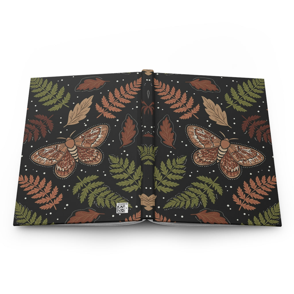 Open book with moth and fern leaf pattern on a white background