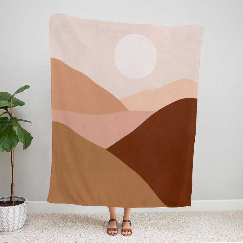 Neutral desert landscape velveteen plush blanket with layered earth tones and abstract hills, person holding up blanket 50x60 inch