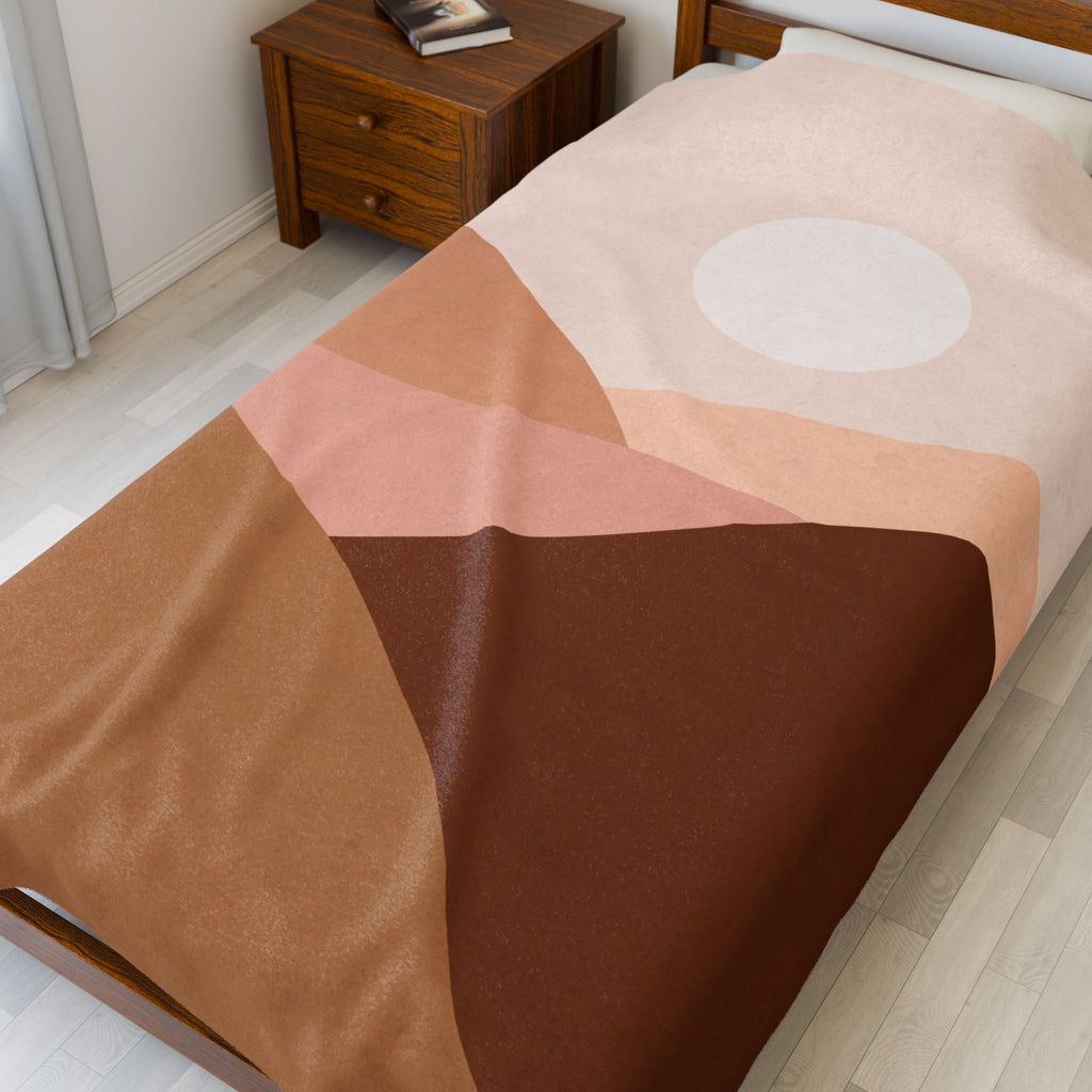 Bed with a brown and pink geometric patterned throw blanket in a bedroom setting.