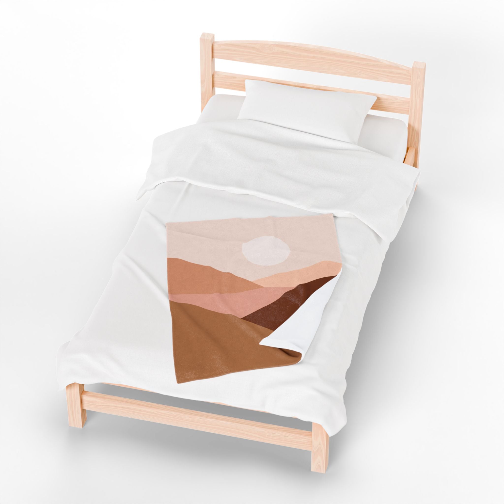 Bed with a  desert landscape-themed throw blanket on a white background