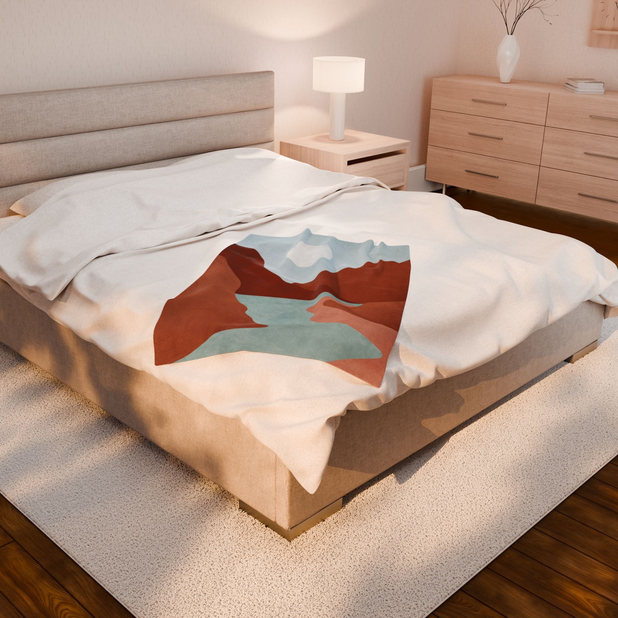 Bed with a colorful mountain landscape design blanket with shades of rust and blue in a bedroom setting