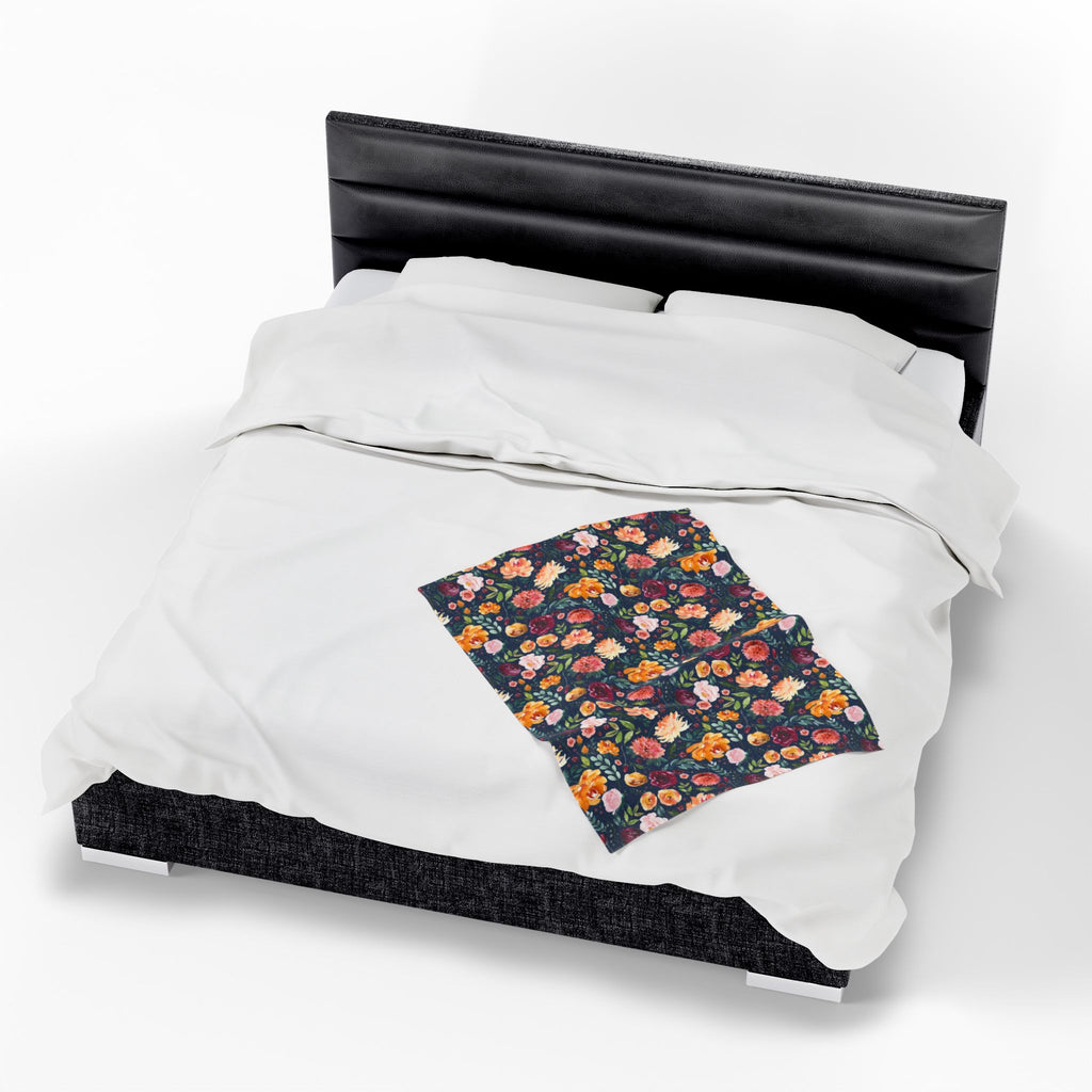 Floral velveteen blanket on a bed with white bedding and black headboard, small lap blanket.