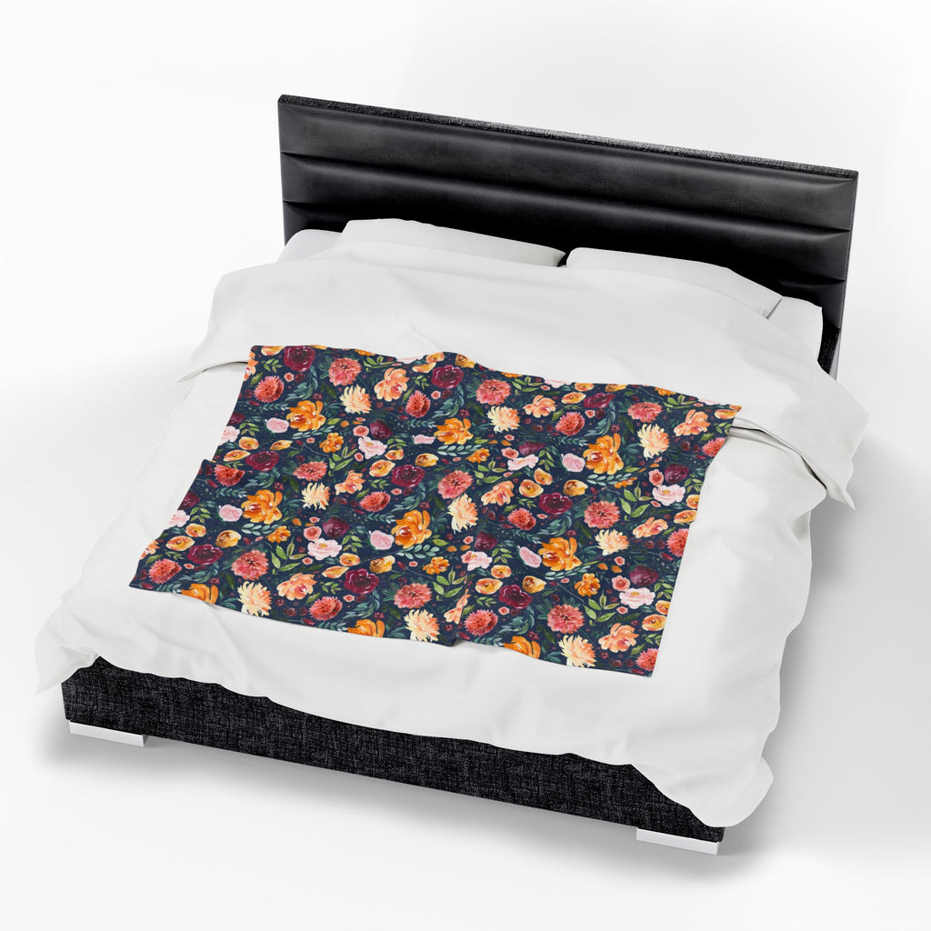 Floral patterned throw blanket on a bed with a black headboard. navy floral blanket