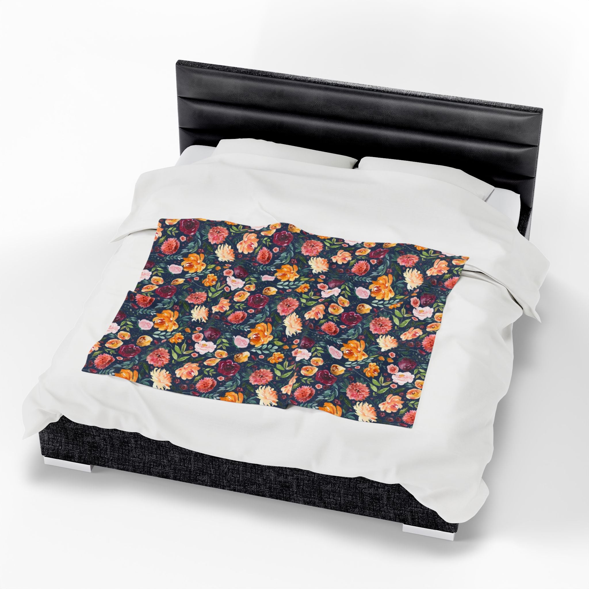 Floral patterned throw blanket on a bed with a black headboard. navy floral blanket