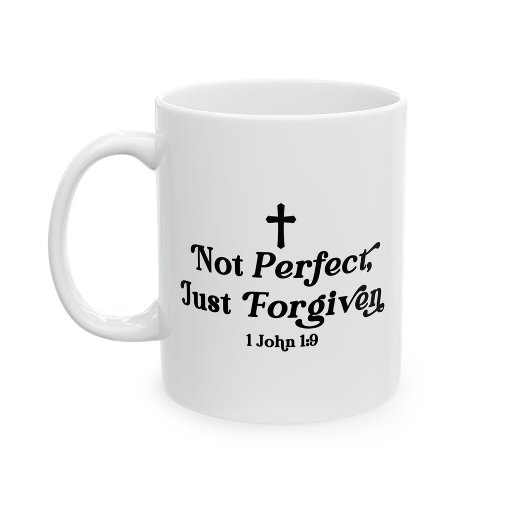 White ceramic Christian mug with black text “Not Perfect, Just Forgiven” and Bible verse 1 John 1:9, featuring a small cross design.