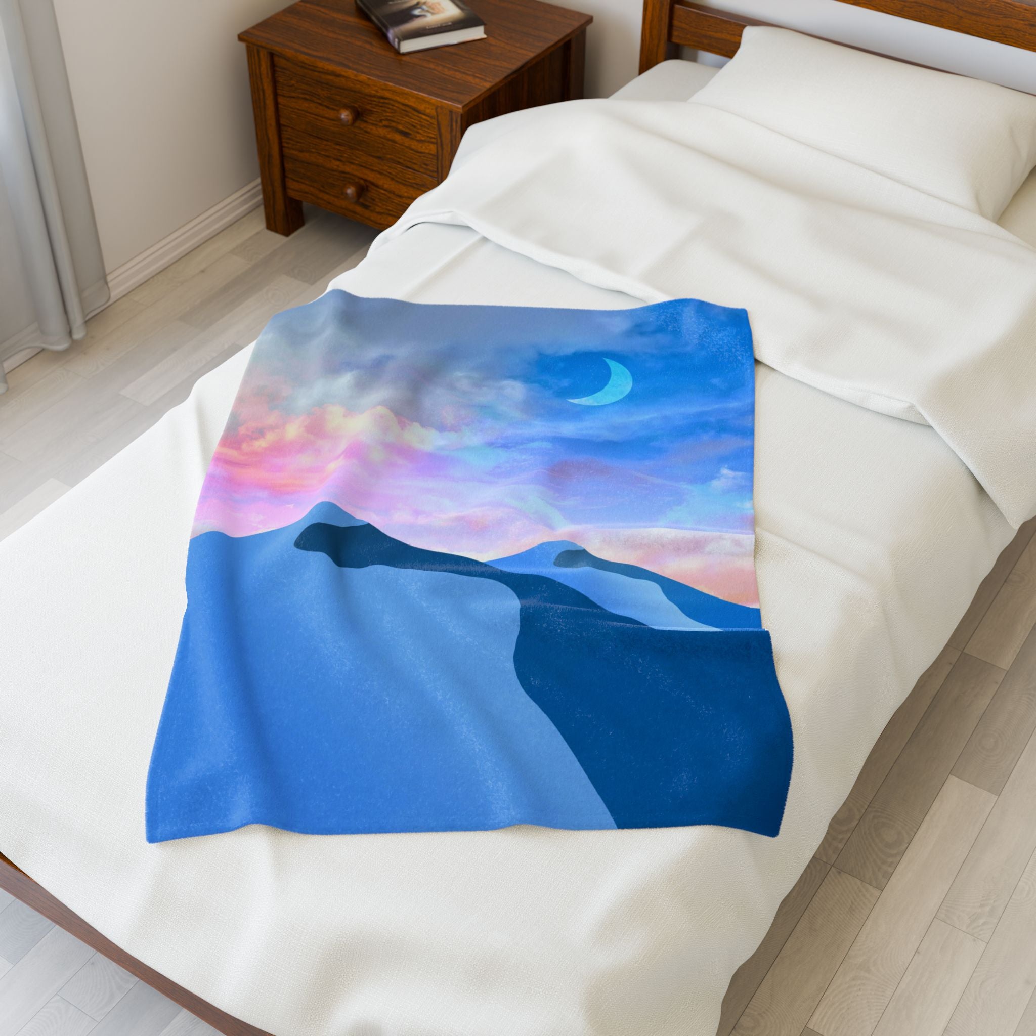 Blanket with a mountain and moon design draped over a bed in a bedroom.