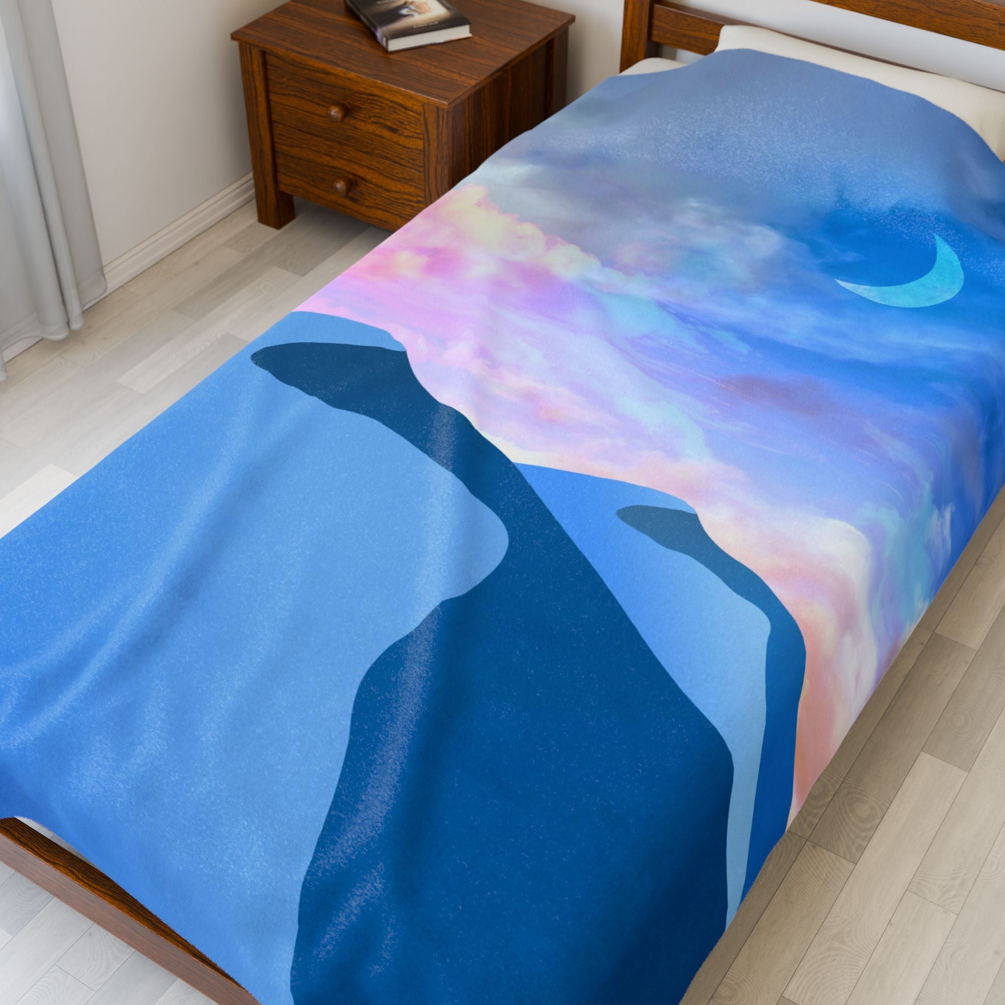 Bed with a colorful blanket featuring Desert mountains and a crescent moon.