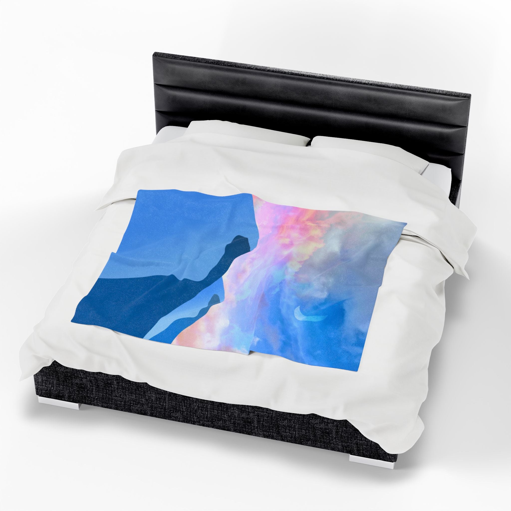 Colorful abstract pastel desert design throw blanket on a white comforter with a black headboard.