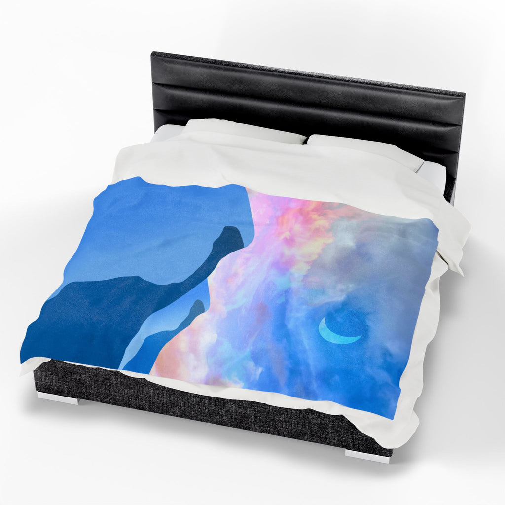 Colorful pastel sky and abstract mountain scene throw blanket on a bed with a black headboard.