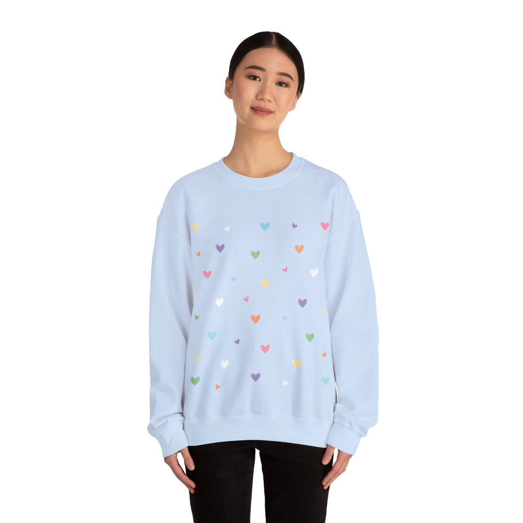 Light blue sweatshirt with colorful heart patterns worn by a person on a white background