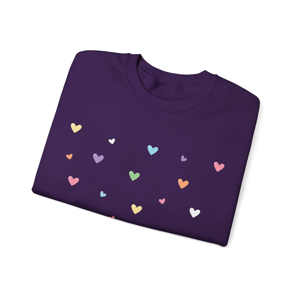 Folded purple sweatshirt with colorful heart patterns on a white background