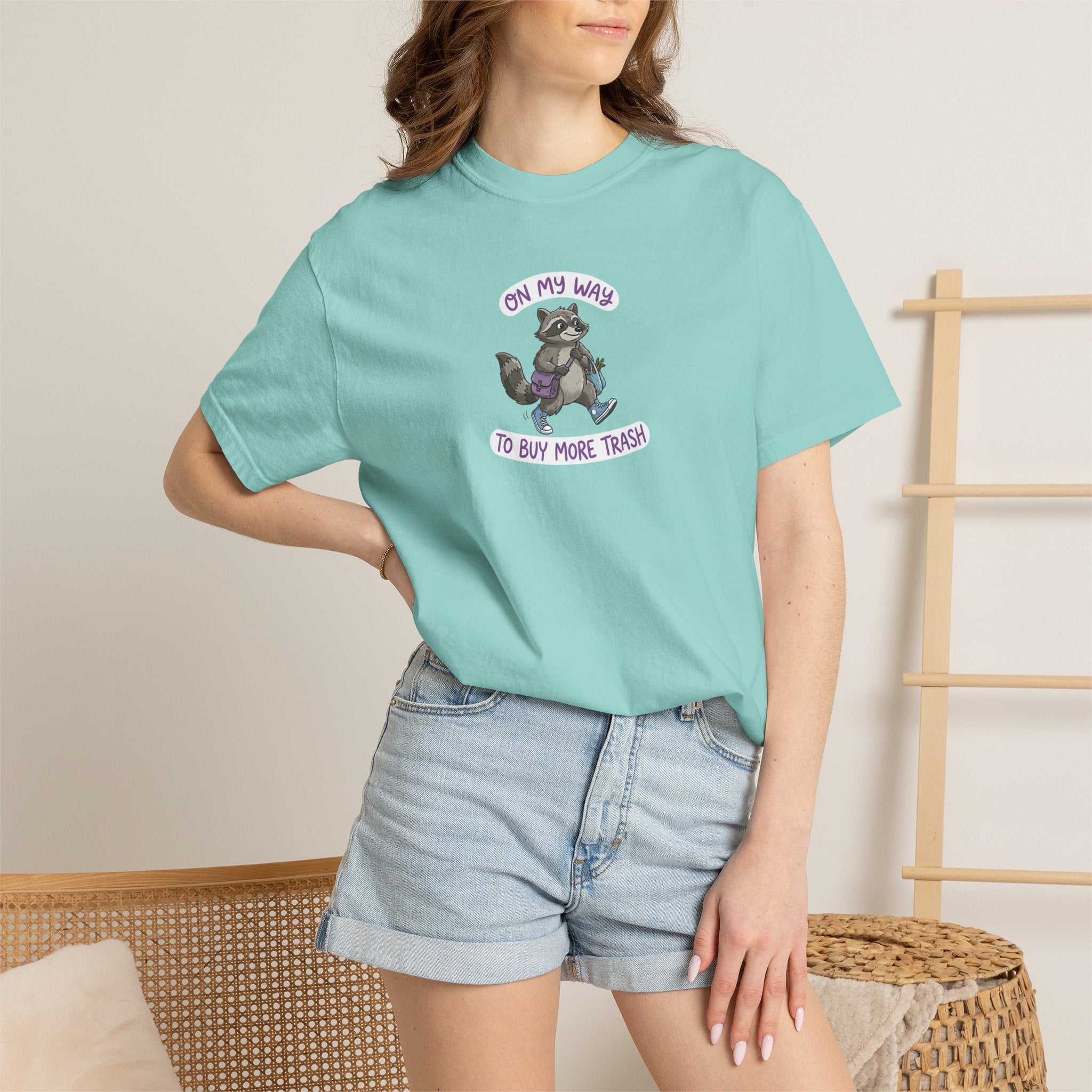 Person wearing a mint t-shirt with a graphic design and text, standing against a neutral background.