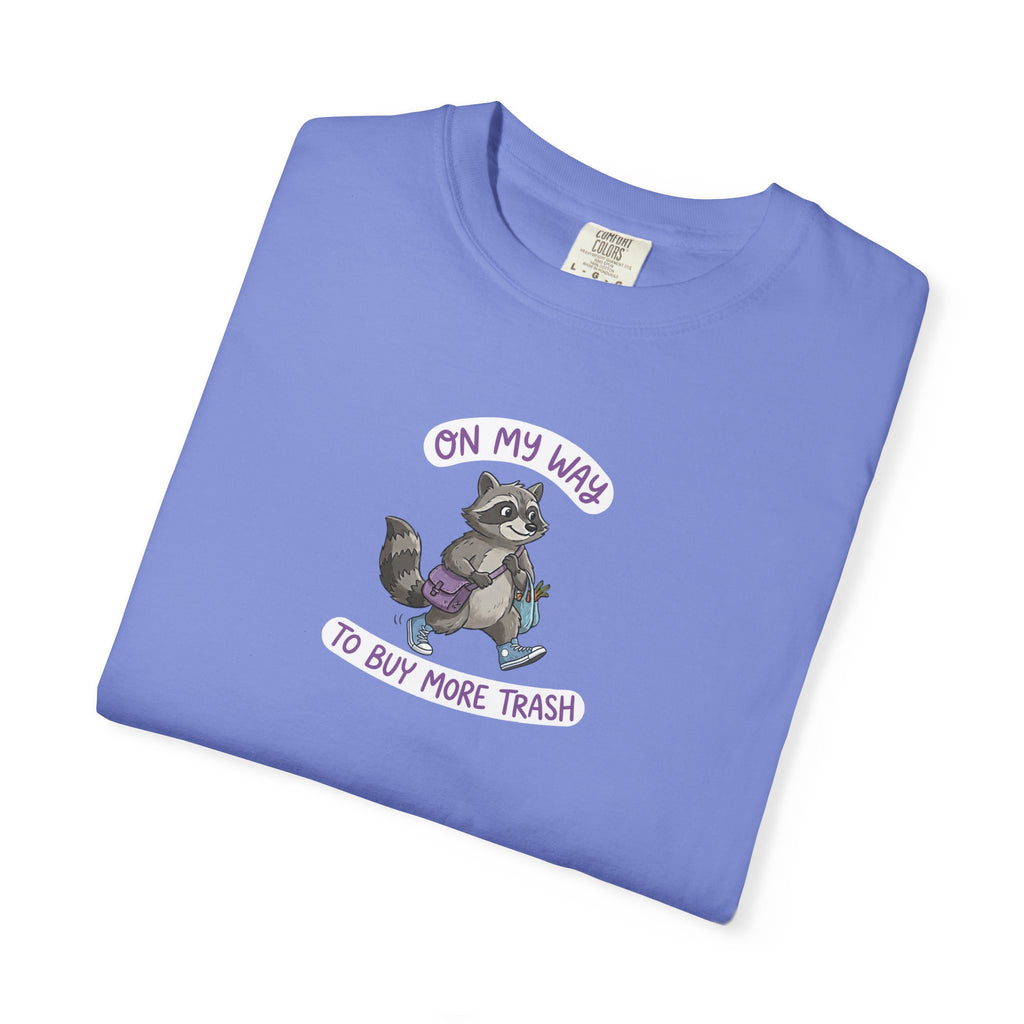 Folded blue t-shirt with a raccoon graphic and text on a white background