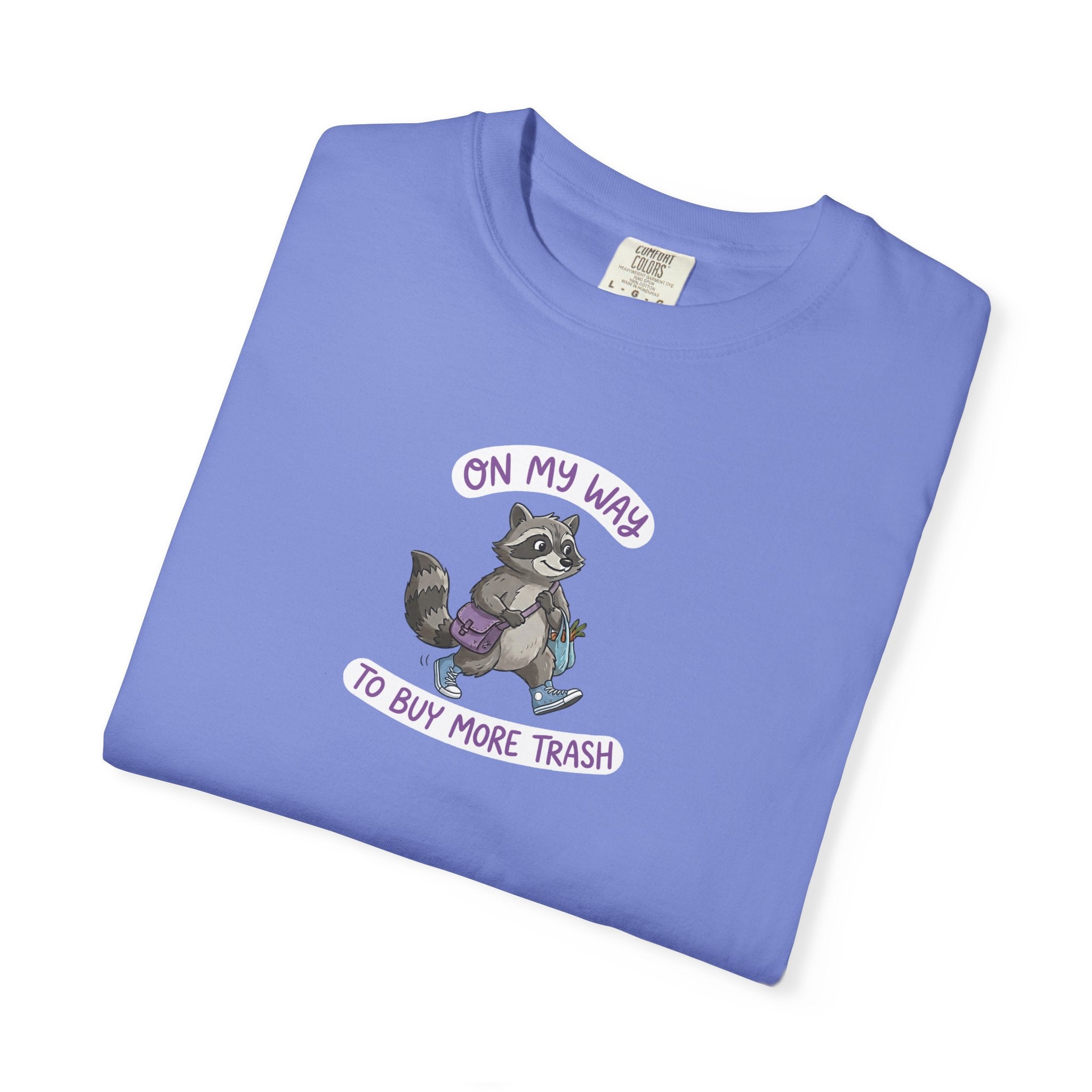 Folded blue t-shirt with a raccoon graphic and text on a white background