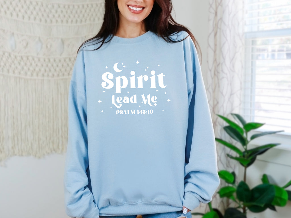 Person wearing a light blue sweatshirt with 'Spirit Lead Me' text, standing indoors. Bible verse sweatshirt